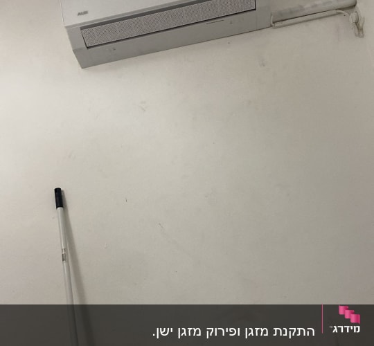 מזגן מותקן על קיר לבן עם צינור חיבור